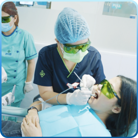 A woman sits in a dentist chair while a female dentist treating her